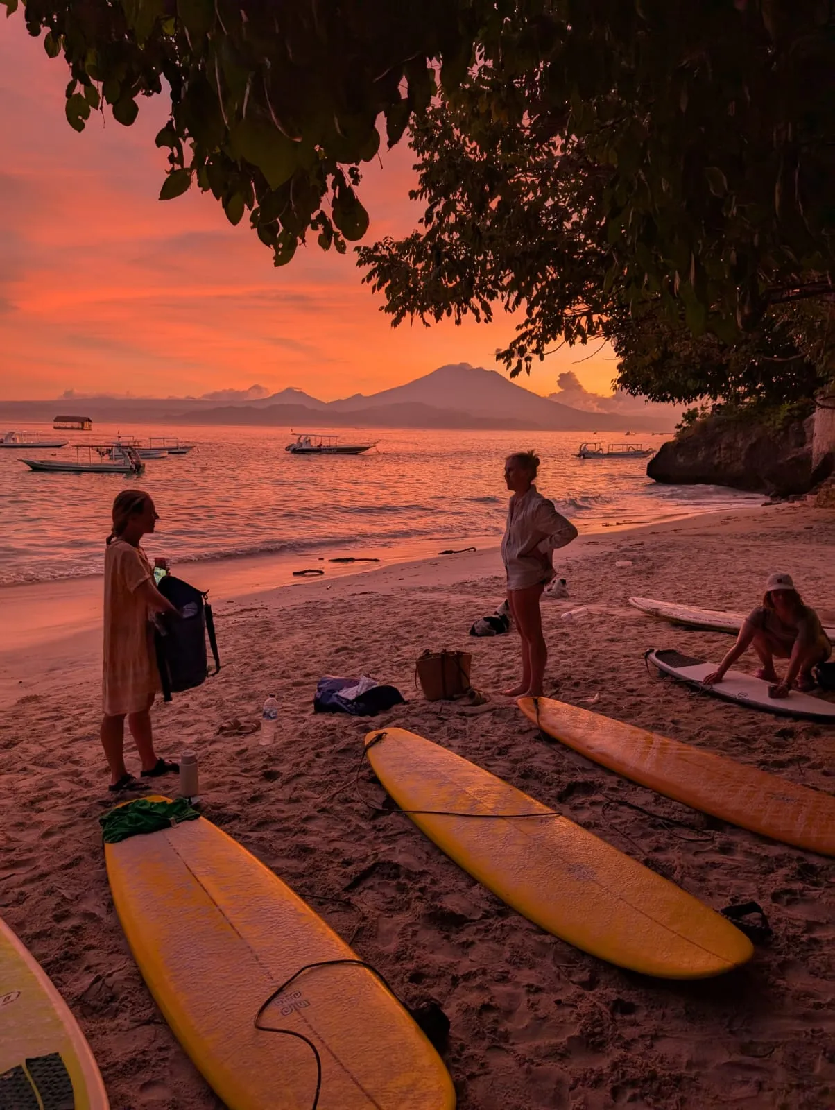 Surfers on the sand at first light off Coconut Beach, Nusa Lembongan, longboards laid out and Mount Agung across the water