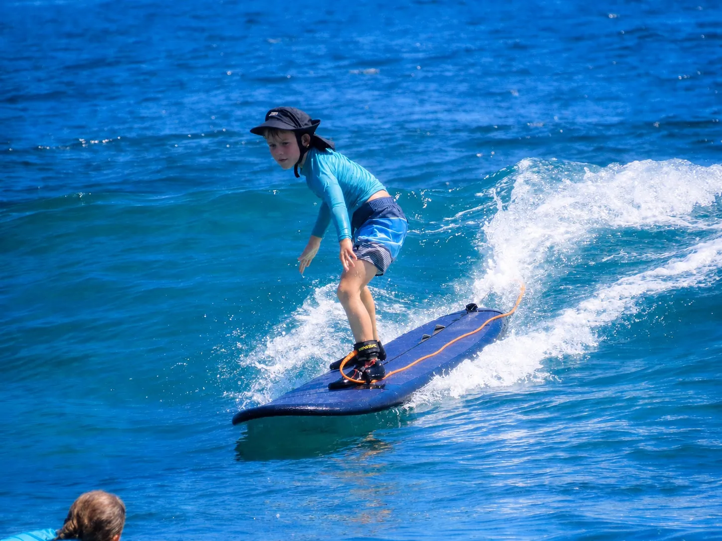 A young beginner riding a wave on a soft board at Nusa Lembongan