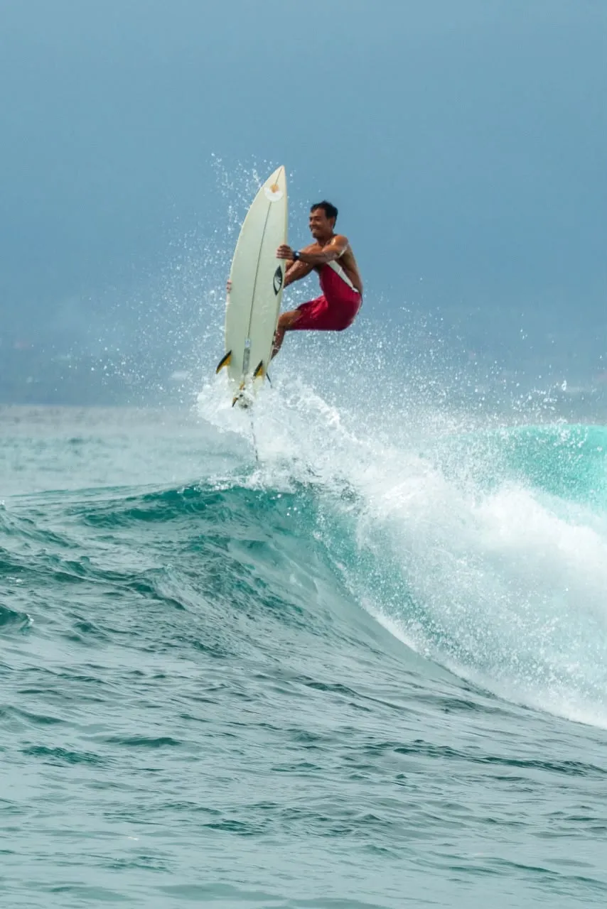 Loxy launching off the lip of a wave at Nusa Lembongan, board vertical and spray flying