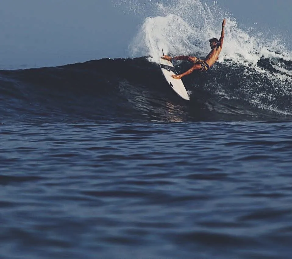Loxy driving off the top of a dark, powerful wall at Shipwrecks, Nusa Lembongan, spray flying