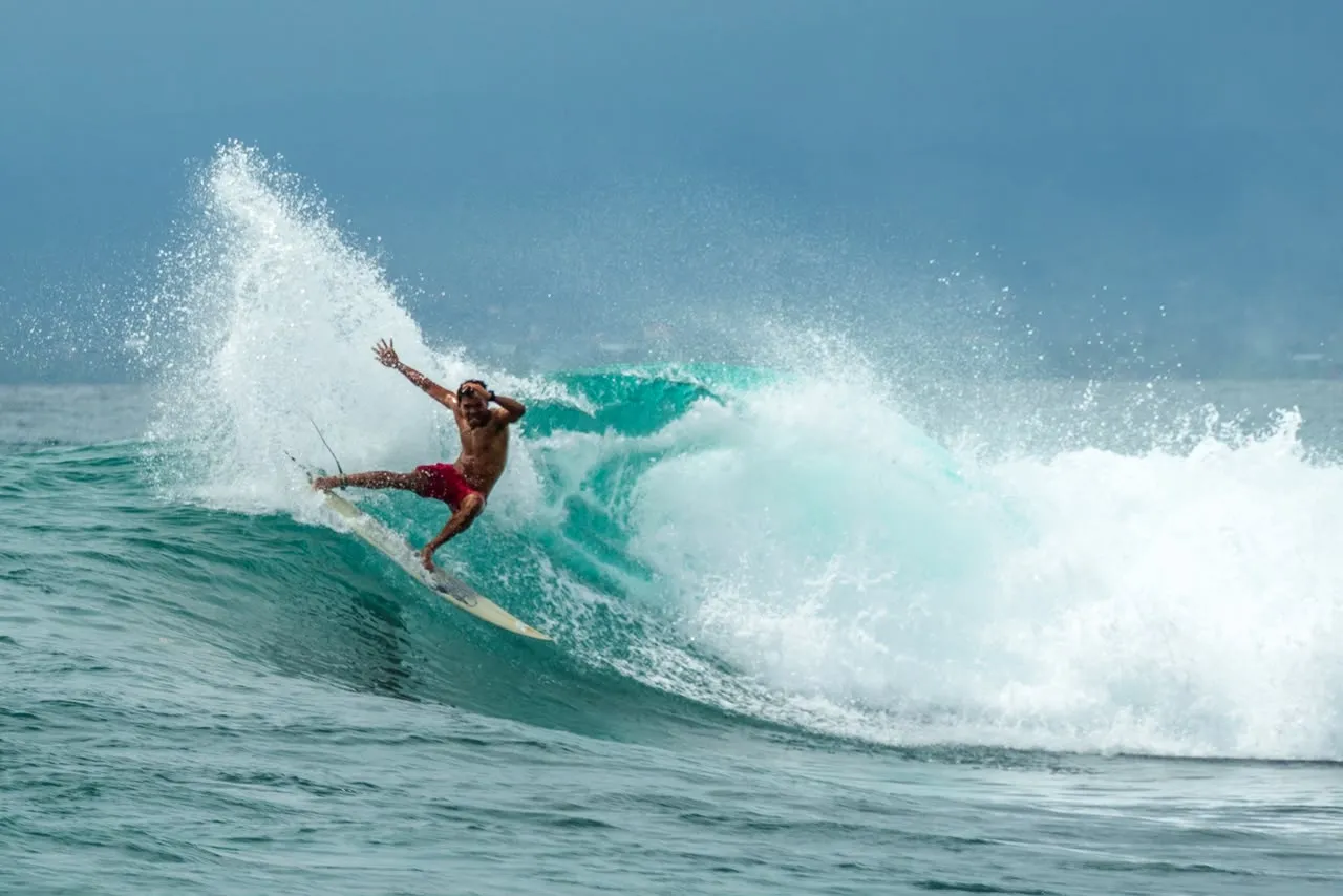 Loxy carving off the top of a turquoise wave at Nusa Lembongan, spray flying