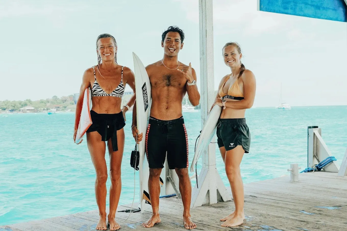 Loxy on the jetty with two happy first-time surfers holding their boards at Nusa Lembongan